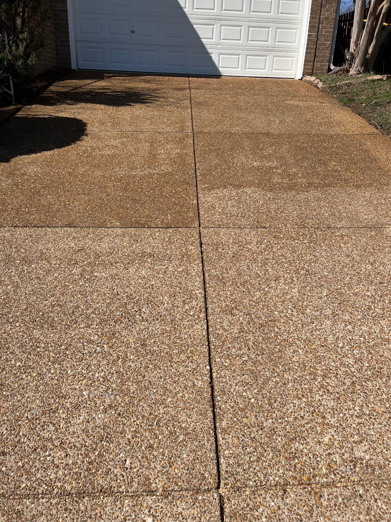 Aggregate driveway in Bellevue mid-project — top half sealed with a natural water-based sealer, bottom half unsealed for comparison