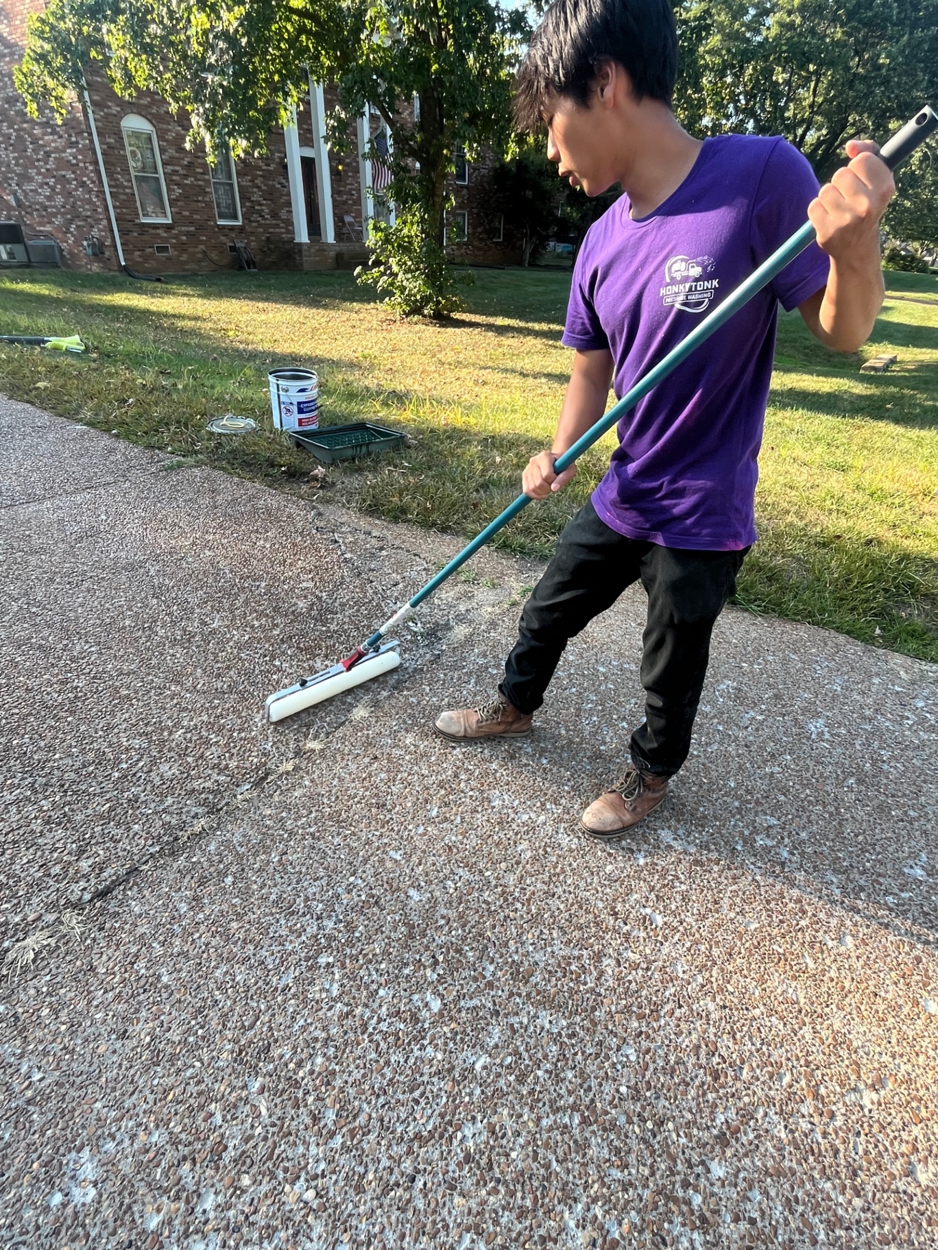 Jack Wehby of Honky Tonk Pressure Washing rolling sealer onto an aggregate driveway in Temple Hills, Nashville
