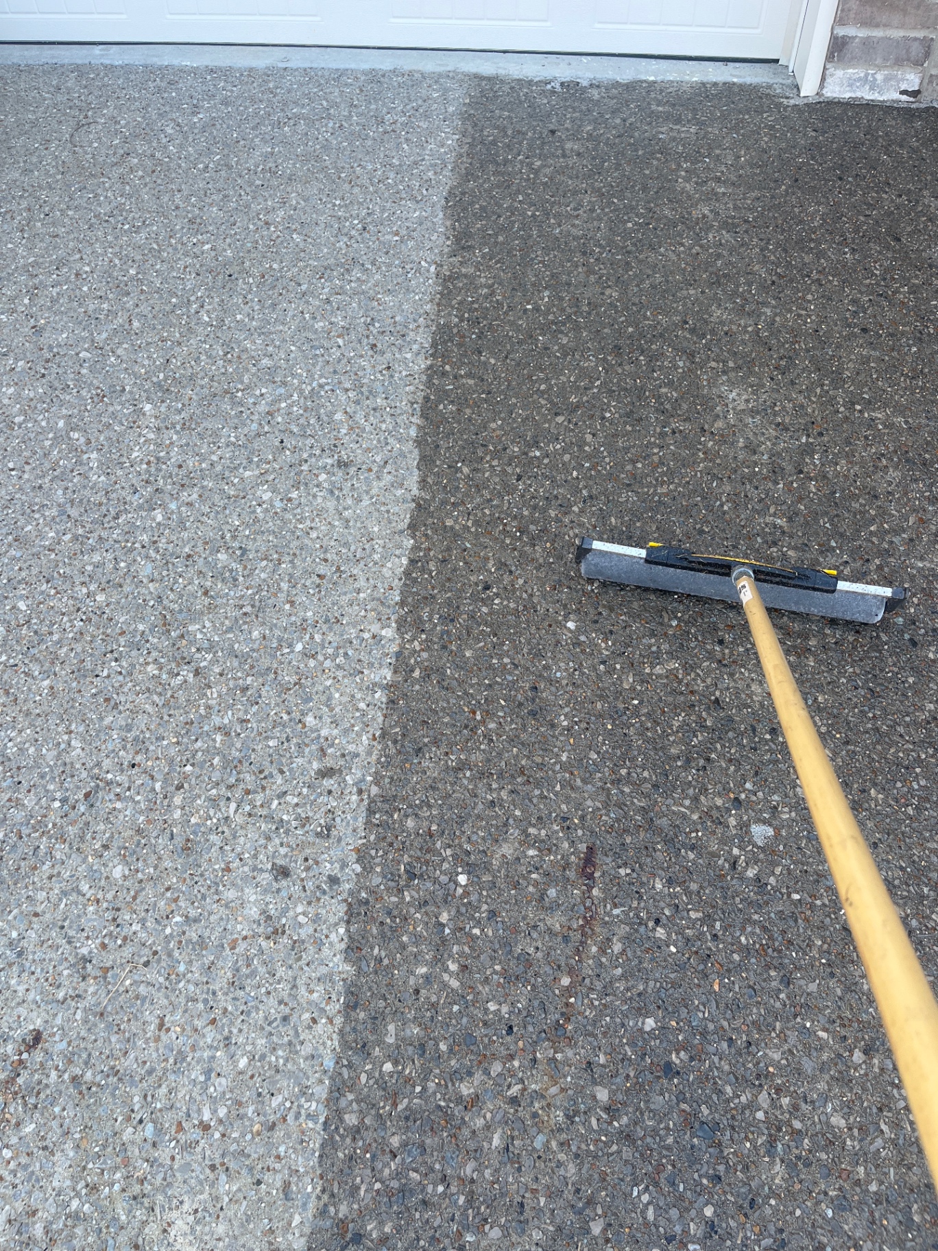Gray aggregate driveway in Nolensville — left side unsealed, right side freshly sealed with acrylic-based sealer, showing a crisp line between the two finishes